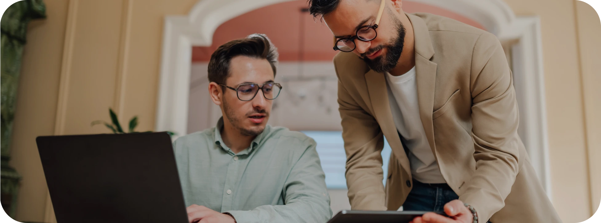 Two professionals collaborating over a laptop while reviewing SMS delivery.